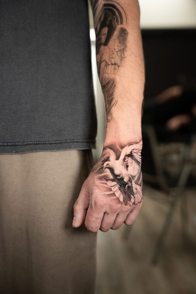 Black and grey realism hand dove tattoo by The KCHN Tattoos, Scarborough
